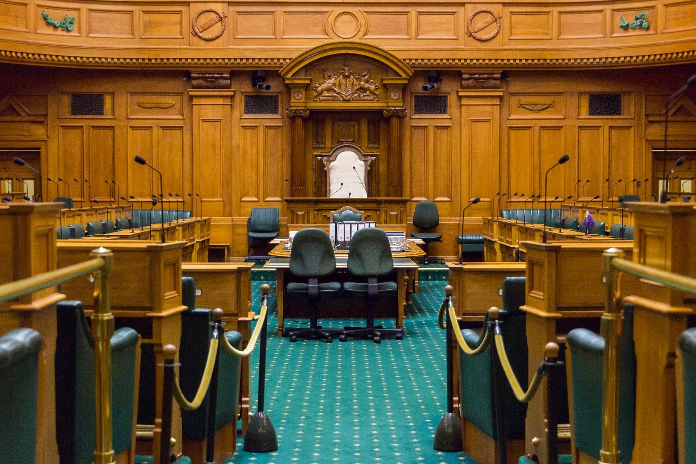 Empty debating chamber showing seating and microphones