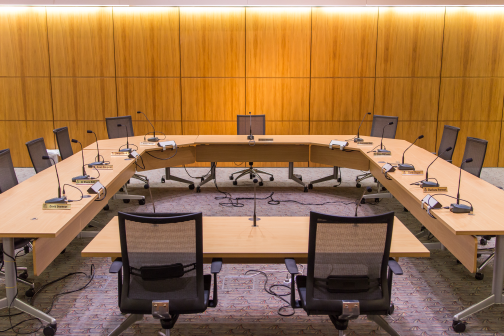 A photo of a u-shaped table formation with 10 chairs around the side